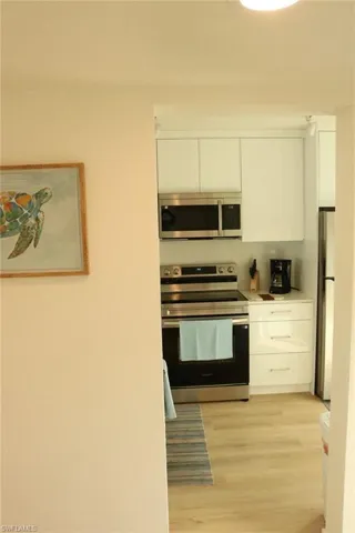 Kitchen featuring light wood-finish flooring, white cabinetry, stainless steel appliances, and a built-in microwave