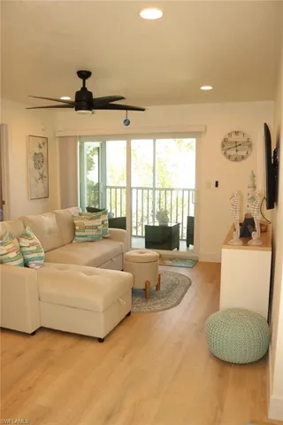 Living area with light wood-finish flooring, recessed ceiling lighting, and a modern ceiling fan