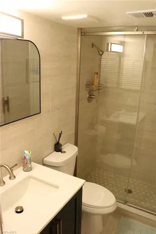 Bathroom featuring a walk-in shower with a glass enclosure, tiled walls, and a pebble-style floor
