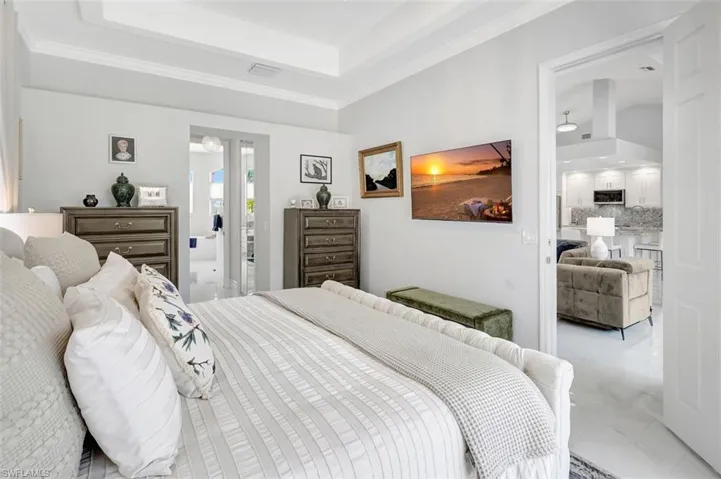 Bedroom featuring marble look tile flooring, a tray ceiling, and crown molding