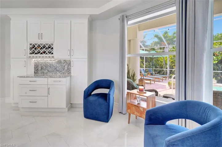 Sitting room with plenty of natural light, light marble finish flooring, and a bar