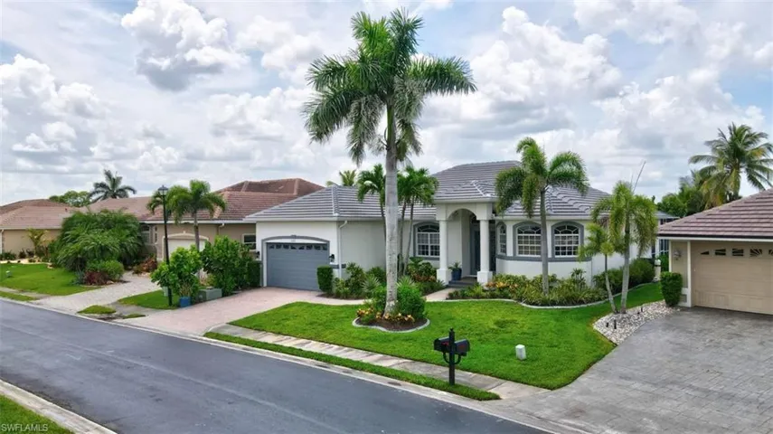 Ranch-style home featuring decorative driveway, stucco siding, a tile roof, a front lawn, and a garage