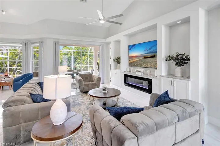 Living room with a fireplace, ceiling fan, and lofted ceiling