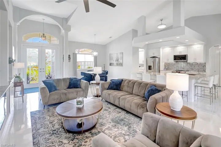 Living room with a ceiling fan, french doors, high vaulted ceiling, decorative columns, and recessed lighting
