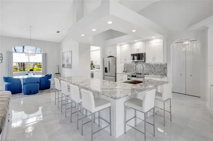 Kitchen with stainless steel appliances, a chandelier, light marble finish flooring, recessed lighting, and a kitchen breakfast bar