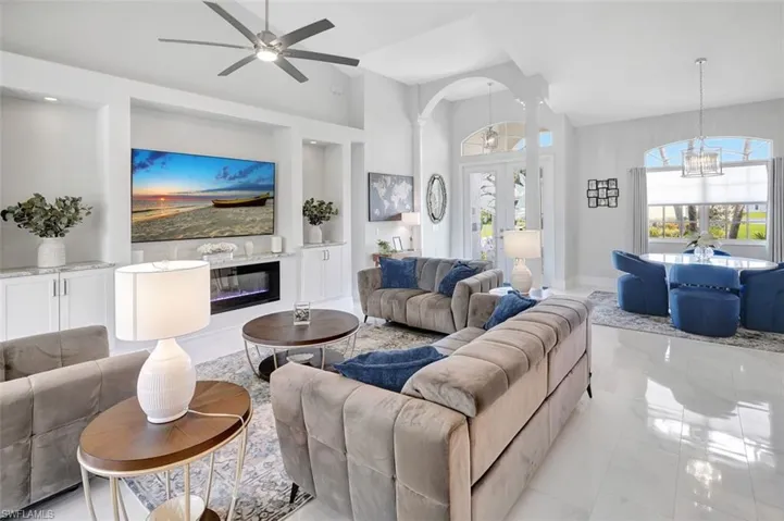 Living area with ceiling fan, french doors, a chandelier, decorative columns, and lofted ceiling