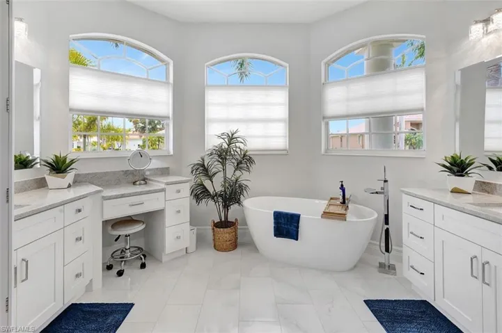 Bathroom with a soaking tub, marble look tiles, and vanity