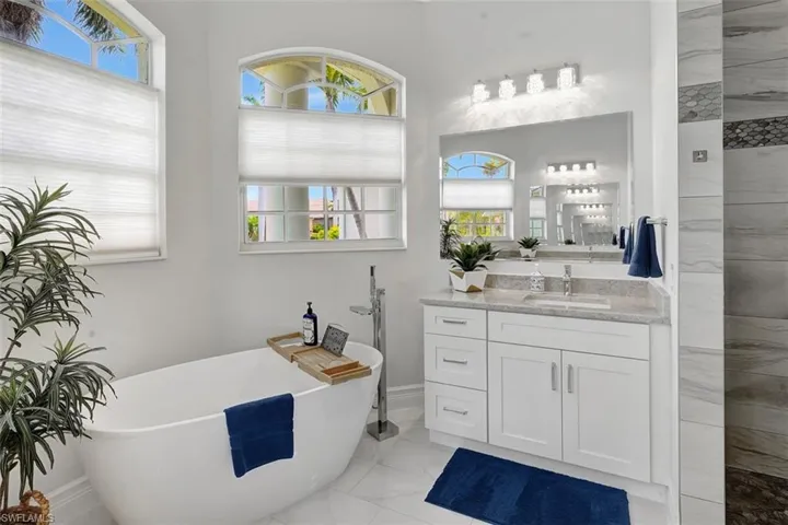 Bathroom featuring marble look tile flooring, a soaking tub, vanity, and tiled shower