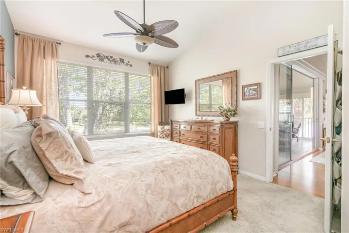 Primary Bedroom featuring light carpet, vaulted ceiling, baseboards, and ceiling fan