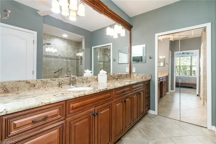 Ensuite bathroom with a shower stall, double vanity, a chandelier, and tile patterned flooring