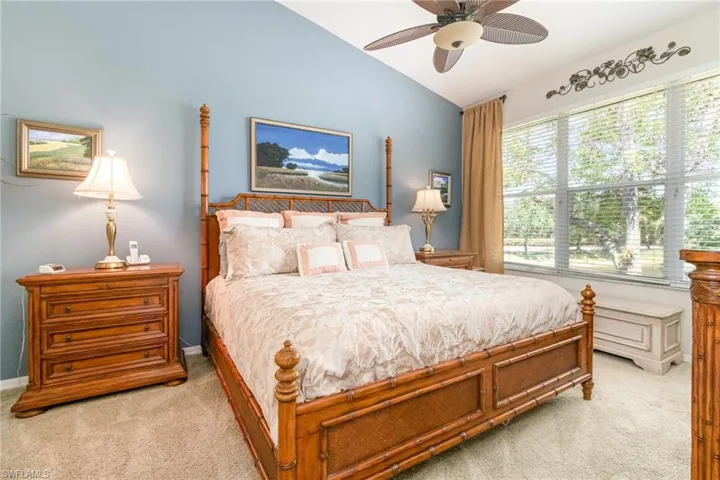 Primary Bedroom with light carpet, vaulted ceiling, ceiling fan, and baseboards