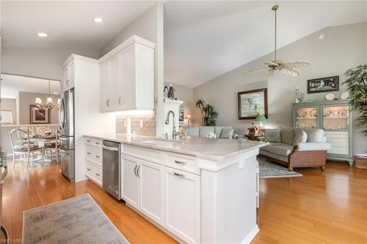 Kitchen featuring appliances with stainless steel finishes, a sink, white cabinetry, light wood-style floors, and vaulted ceiling