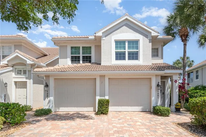 View of front of house with decorative driveway, stucco siding, and a tiled roof
