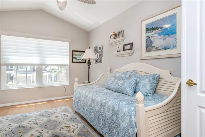 Den-Bedroom featuring wood finished floors, vaulted ceiling, baseboards, and a ceiling fan