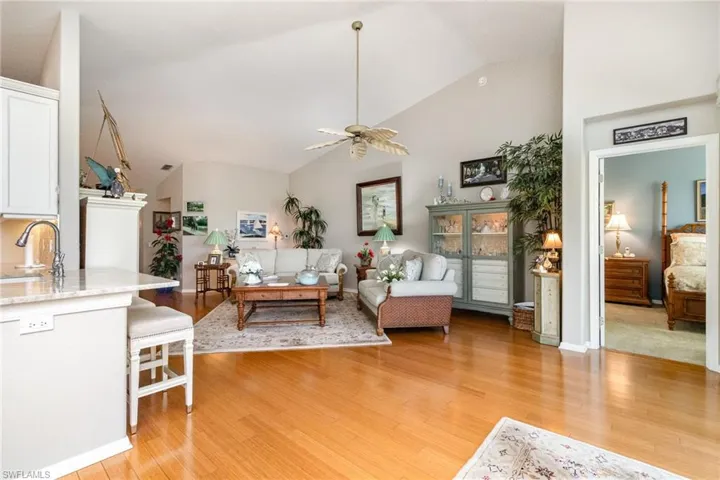 Living room featuring a ceiling fan, light wood-style flooring, high vaulted ceiling, and baseboards