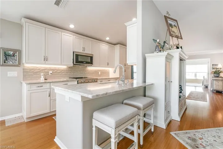 Kitchen featuring appliances with stainless steel finishes, a sink, light wood finished floors, decorative backsplash, and recessed lighting