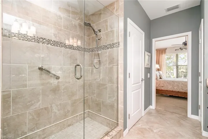 Full bathroom featuring ensuite bath, a shower stall, and baseboards