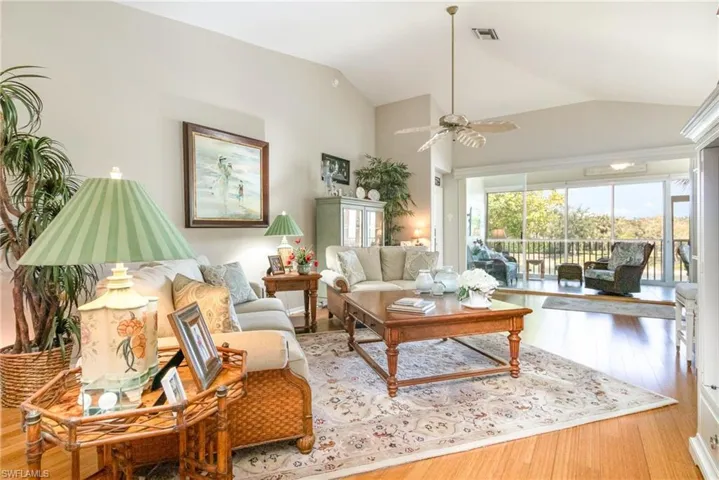 Living room with lofted ceiling, ceiling fan, and wood finished floors