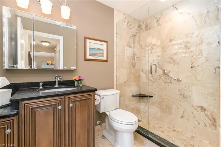 Full guest bath featuring toilet, a shower stall, and vanity