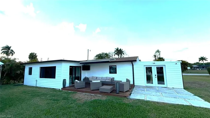 Back of house featuring outdoor furniture, a lawn, french doors, and a deck