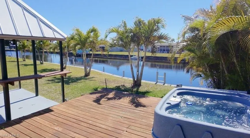Deck with a yard, a water view, and a hot tub