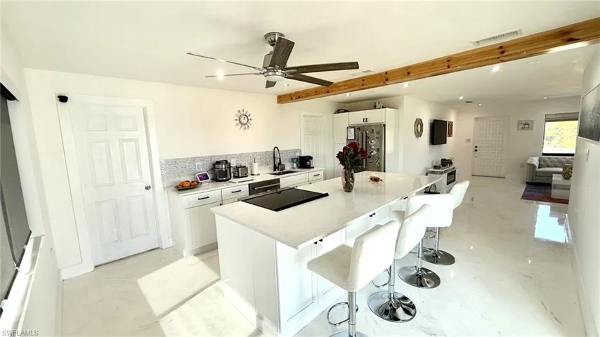 Kitchen featuring white cabinetry, black appliances, a kitchen bar, a kitchen island, and tasteful backsplash
