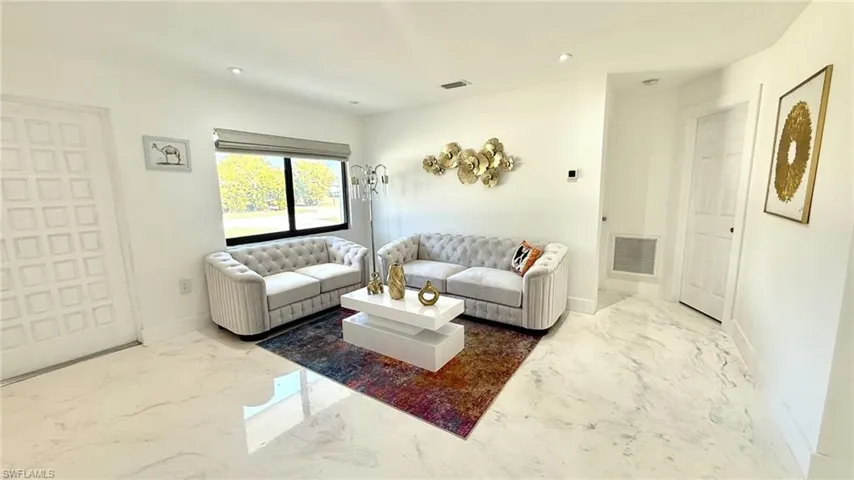 Living area featuring light marble finish flooring and recessed lighting