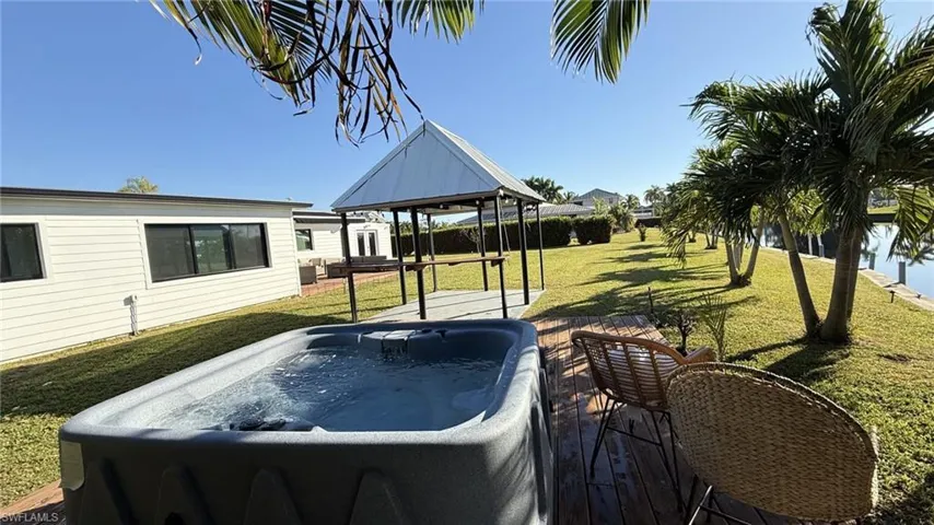 View of green lawn featuring a hot tub, a gazebo, and a deck