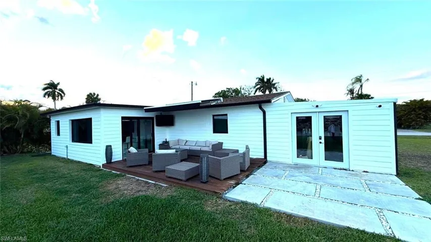 Rear view of property featuring outdoor furniture, a lawn, a deck, and french doors