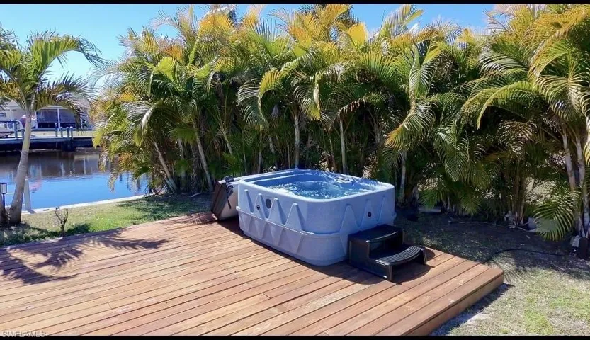 Wooden terrace with a hot tub and a water view