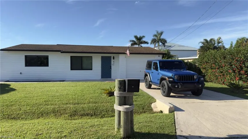Ranch-style home featuring a front yard, driveway, and an attached garage