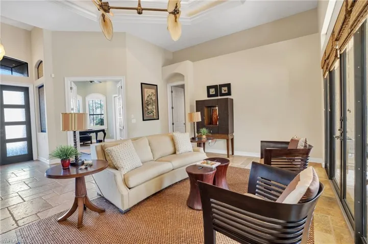 Living area featuring stone tile floors, a high tray ceiling, and arched walkways