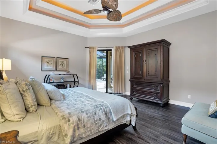 Bedroom featuring access to exterior, dark wood-style flooring, a ceiling fan, ornamental molding, and a raised ceiling