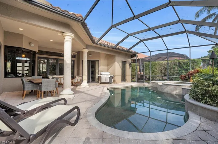 Combined pool / hot tub featuring a sunroom, outdoor dining space, a patio area, a lanai, and a grill