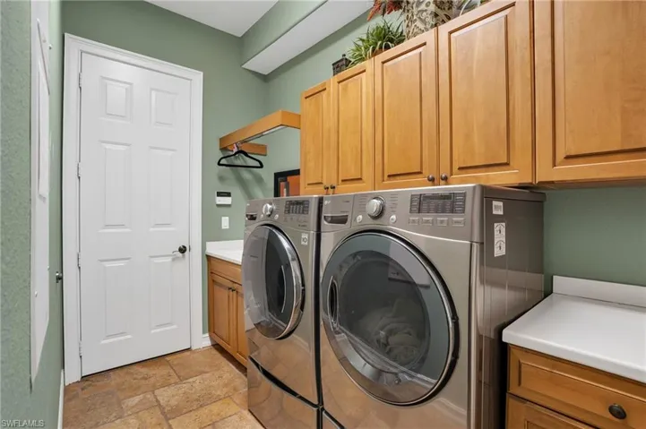 Laundry room featuring stone tile flooring, independent washer and dryer, and cabinet space