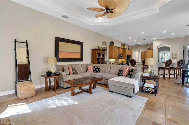 Living area featuring stone tile floors, ceiling fan, ornamental molding, arched walkways, and recessed lighting