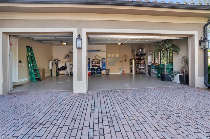 Garage featuring electric water heater, decorative driveway, and electric panel