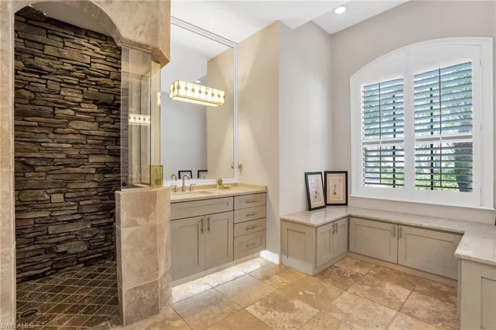 Bathroom featuring vanity, a walk in shower, and stone tile floors