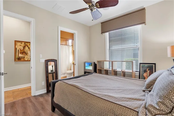 Bedroom with a ceiling fan, wood finished floors, and ensuite bathroom
