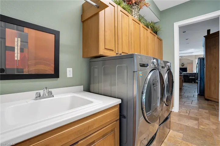 Laundry area featuring stone tile floors, independent washer and dryer, and cabinet space