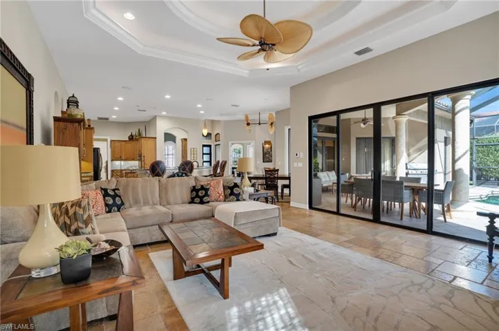 Living area with stone tile flooring, ceiling fan, recessed lighting, crown molding, and a raised ceiling