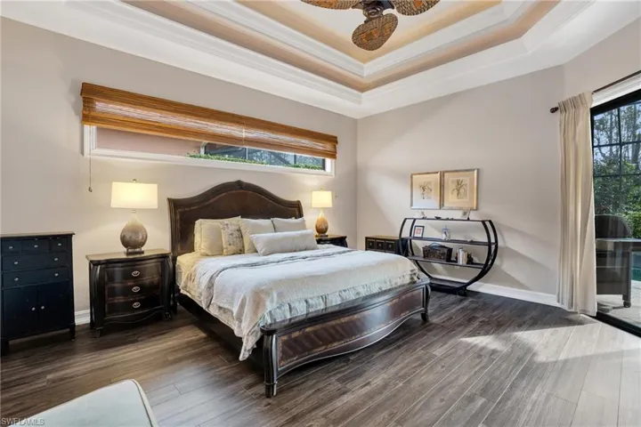 Bedroom with dark wood-type flooring, crown molding, ceiling fan, and access to exterior