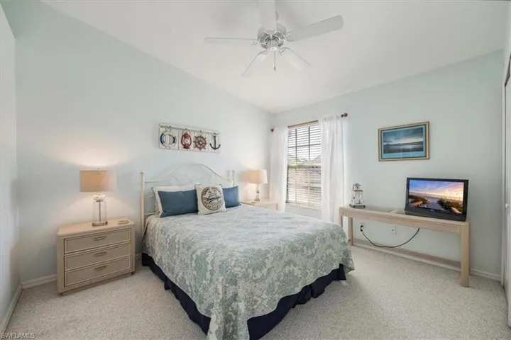 Bedroom with baseboards, a ceiling fan, vaulted ceiling, and light colored carpet