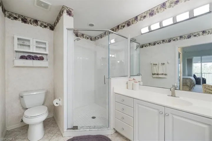 Full bath with vanity, a shower stall, toilet, and visible vents