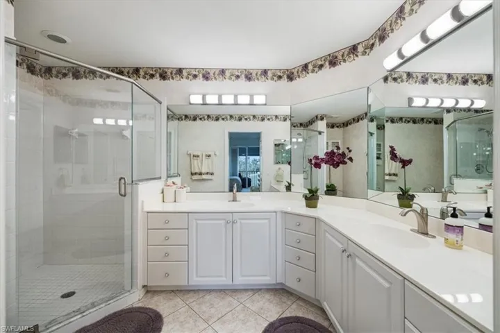 Bathroom featuring double vanity, a sink, tile patterned floors, and a shower stall