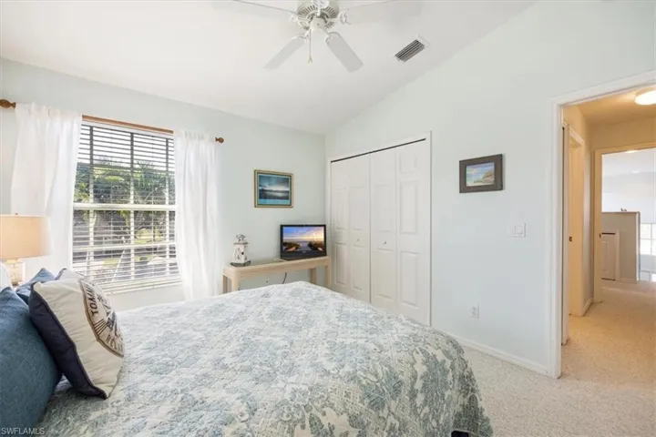 Carpeted bedroom with visible vents, a closet, baseboards, ceiling fan, and vaulted ceiling