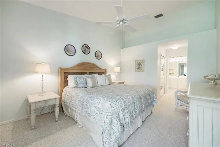 Bedroom featuring visible vents, a ceiling fan, connected bathroom, and light colored carpet