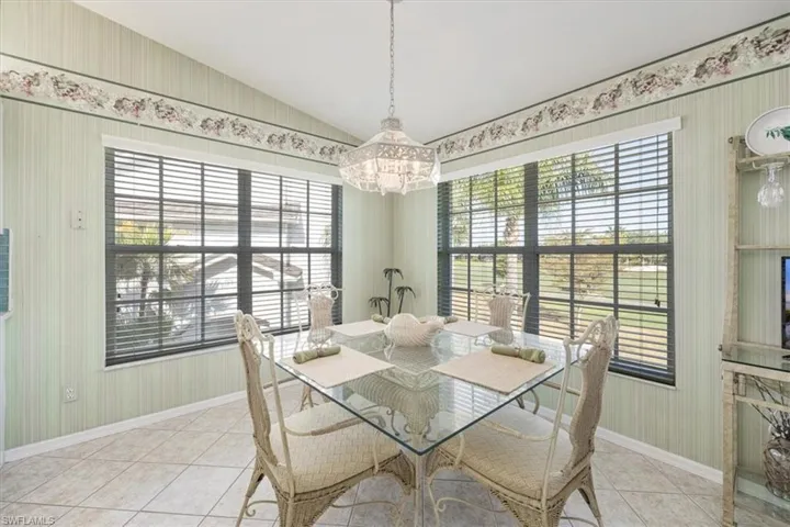 Dining area with baseboards, light tile patterned flooring, a notable chandelier, and a healthy amount of sunlight
