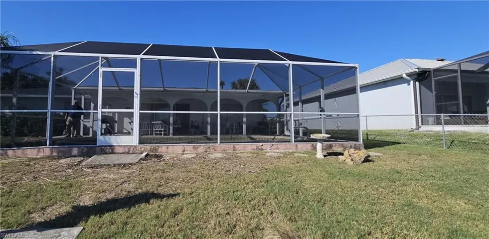 Back of house featuring a lawn and a lanai