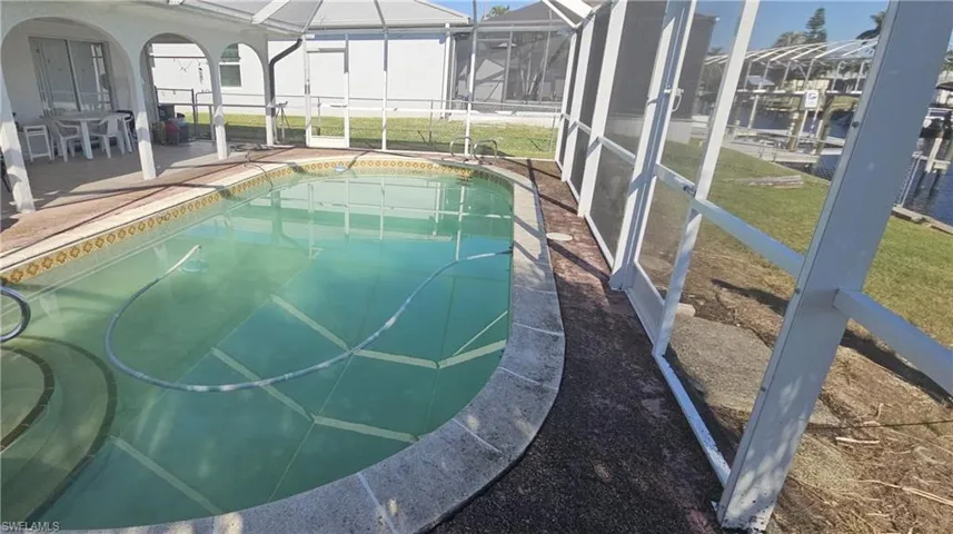 View of pool featuring a patio, glass enclosure, and a lawn